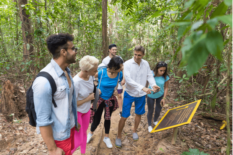 Group touring a forest and reading a marker.